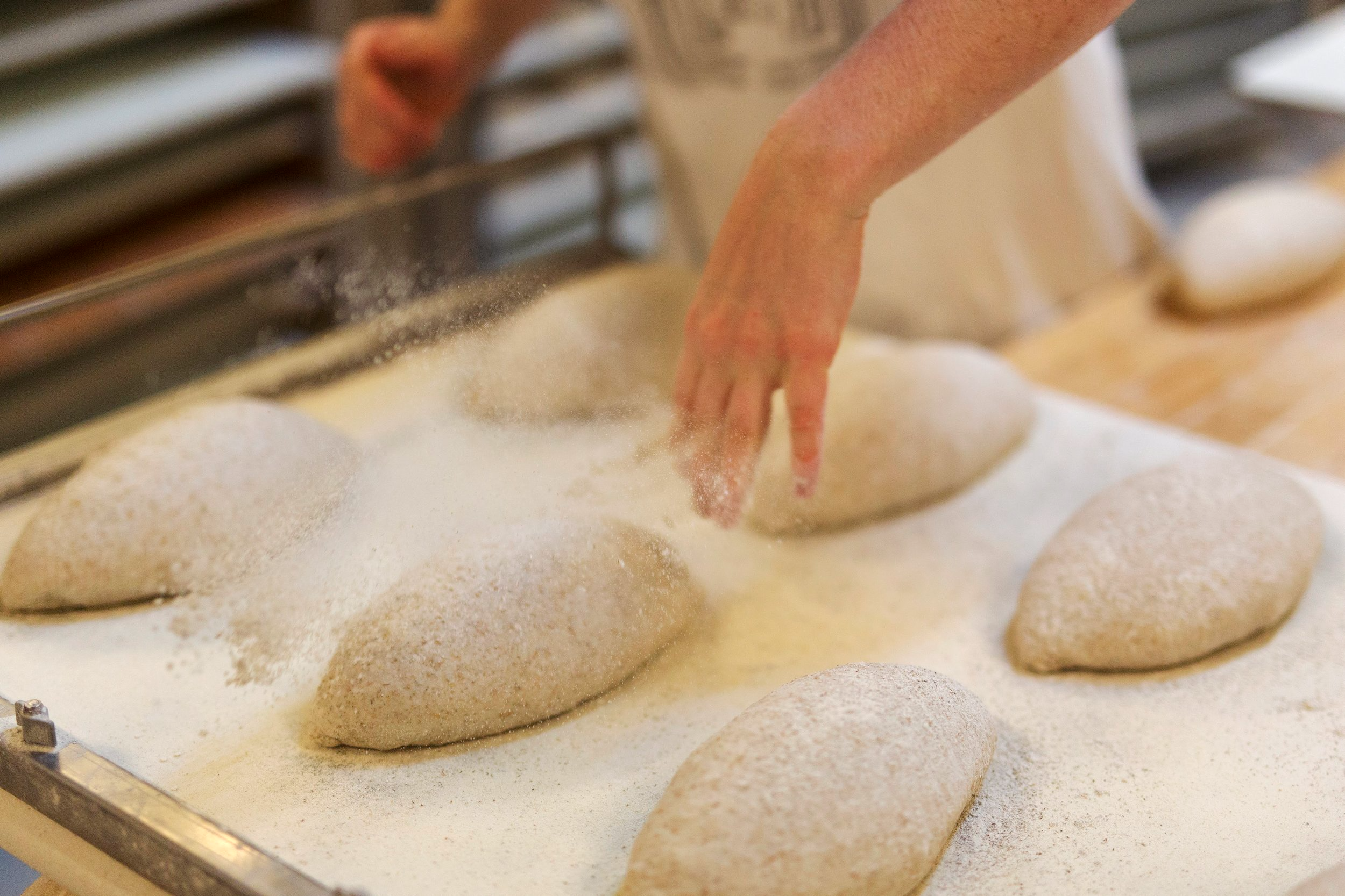 Baker drysser mel over surdeigsbr&oslash;d